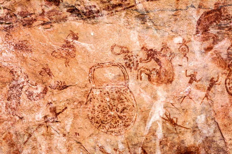 Detalle de escena en un campamento. Mujeres sentadas, algunas con nio a la espalda, preparan los alimentos que salen de una mochila. Una gran mochila- bolso, posiblemente con pedazos de carne, est ubicada emblemticamente en medio del campamento, mientras los hombres cazadores se ven jubilosos y en movimiento. Abajo a la derecha se observa un atento jaguar estilizado. 